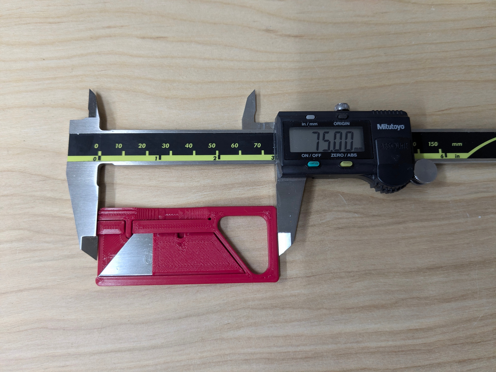 Custom Assista utility knife next to calipers showing 75mm length